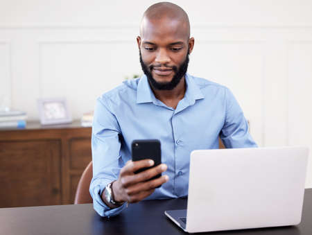 I have an important meeting coming up. Shot of a young businessman using his cellphone while sitting...