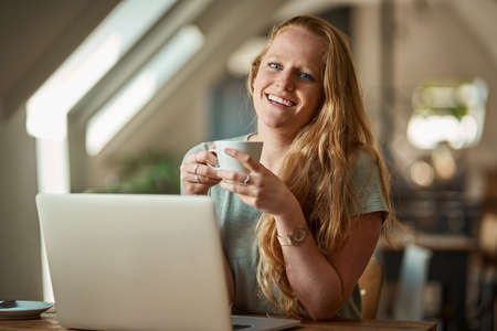 Blogging is just better when its done with free wifi. Shot of a young woman using her laptop in a...