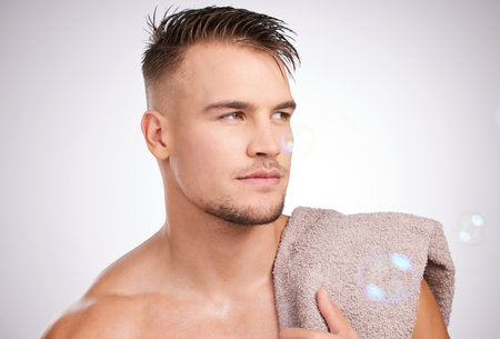 Looking good from every angle. Shot of a young man holding a towel against a grey background.の写真素材