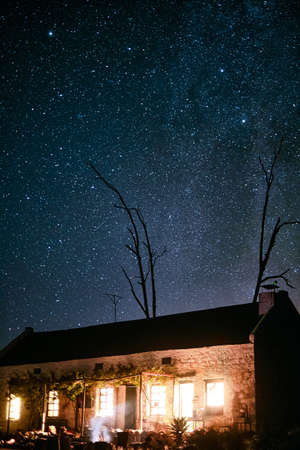 Leave the lights on, Im coming home. Shot of a house in the countryside on a dark starry night.