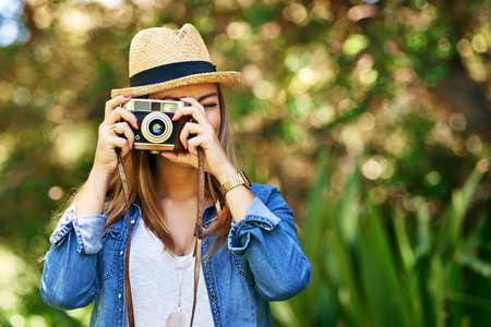 Smile. Shot of an attractive young woman taking photographs outside.