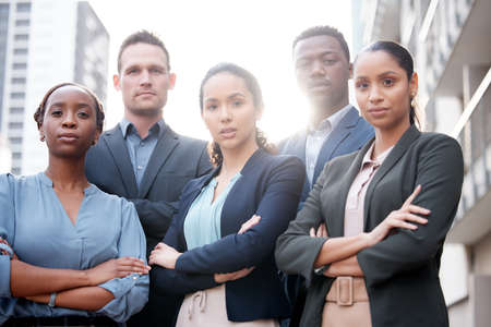 We strive for corporate excellence. Shot of a group of young businesspeople standing with their arms crossed against a city background.の写真素材