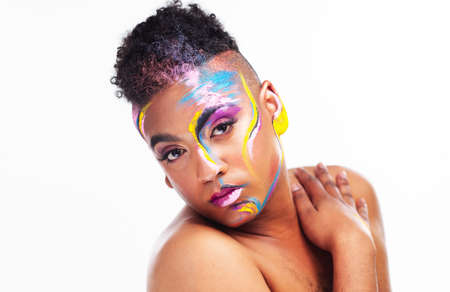 I am who I am. Portrait of a gender fluid young man wearing face paint against a white background.
