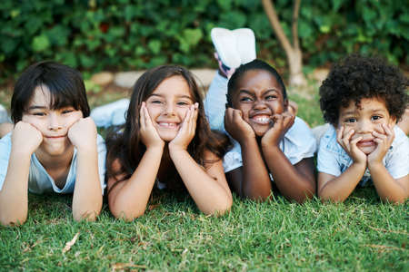 Today has been so much fun. Shot of four adorable kids lying together on the lawn.