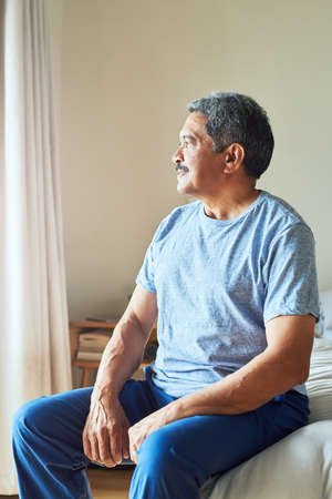 Today is going to be a great day. Shot of a confident mature man looking outside trough his window...