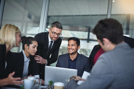 This idea will grab everybodys attention. Shot of a group of businesspeople having a meeting together over a laptop in a boardroom at the office.の写真素材