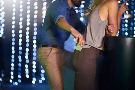 Hide it or lose it. Cropped shot of a man stealing a womans phone from her pants pocket in a...
