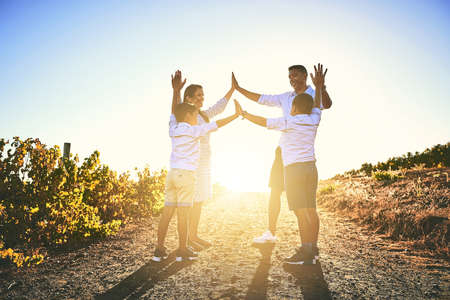 High five for some fun family times. Shot of a happy family high fiving together outdoors.の写真素材