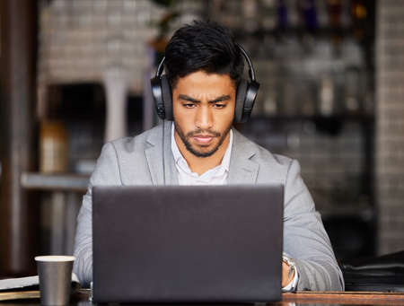 Music gets me in serious business mode. Shot of a young businessman wearing headphones while using a...