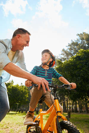 Dads got you. Shot of a father teaching his son how to ride a bicycle.の写真素材