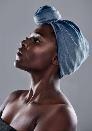 I respect and take good care of myself. Shot of a beautiful young woman wearing a denim head wrap while posing against a grey background.の写真素材