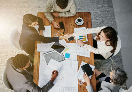Theres a new addition to the team. High angle shot of businesspeople shaking hands during a meeting...