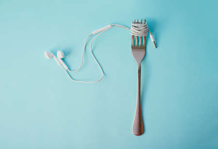 Soul food. Studio shot of earphones wrapped around a fork against a blue background.の写真素材