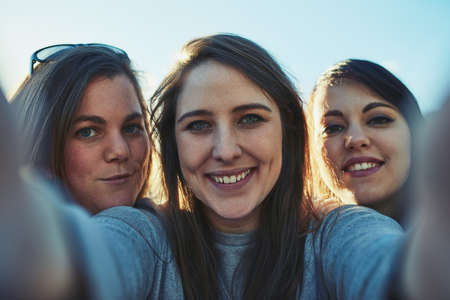 Memories from our greatest summer together. Portrait of a group of women taking a selfie together outdoors.の写真素材