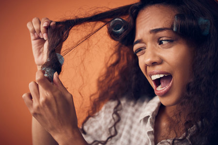 My momma said you gotta suffer for beauty. Shot of a woman pulling hair rollers out of her hair.の写真素材