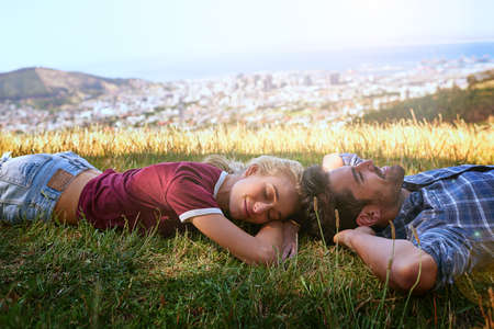 Sleeping on the mountain top. Shot of an affectionate young couple enjoying a day outdoors.の写真素材