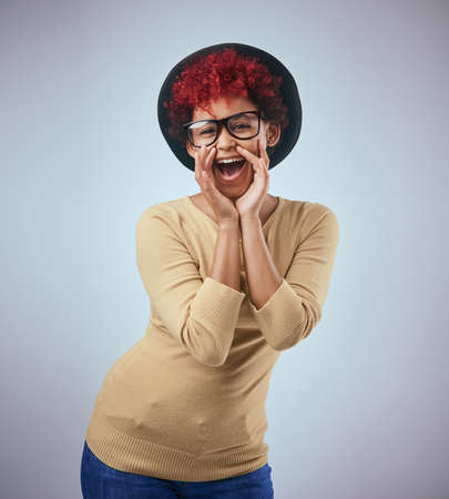 Im spreading the word. Studio shot of a beautiful young woman wearing a hat against a grey...