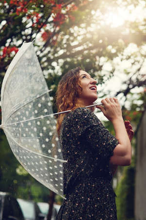 She loves all the elements of nature. Cropped shot of a beautiful young woman walking in the rain outside.の写真素材
