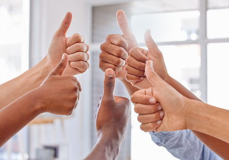 Thumbs up for teamwork. Cropped shot of a group of unrecognizable people showing thumbs up in an...