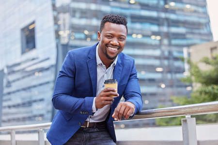 Just the boost I needed. Shot of a young businessman drinking a cup of coffee against a city...