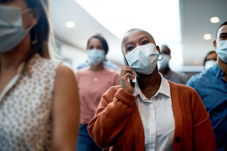 Get going, get ahead. Shot of a masked young businesswoman using a smartphone during a conference.の写真素材