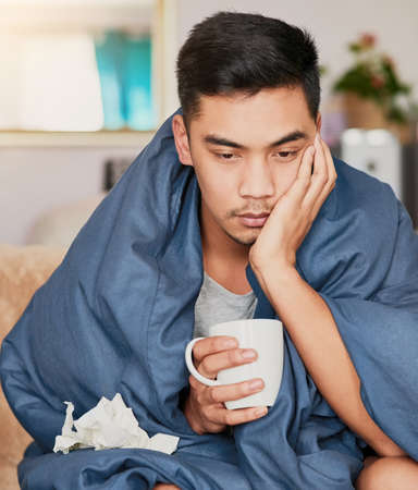 Nothing fun about the flu. Shot of a young man with a cold recuperating at home.