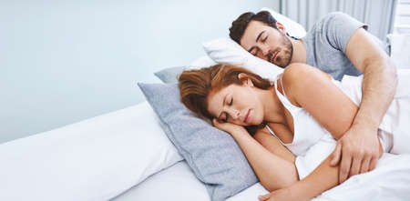 Enjoying their weekend lie in. Shot of a couple sleeping in bed together at home.の写真素材