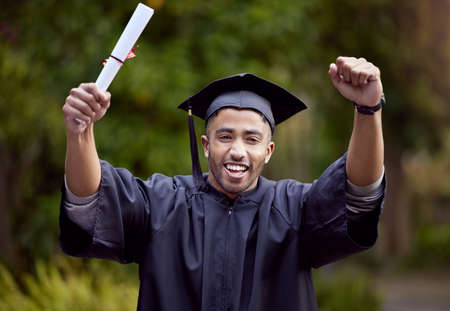 In the end, its all worth it. Shot of a young man looking cheerful on graduation day.