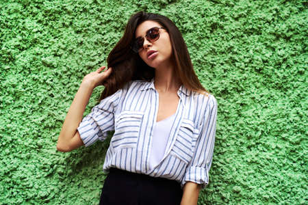 Shes confidence personified. Cropped shot of an attractive young woman standing against a green wall...
