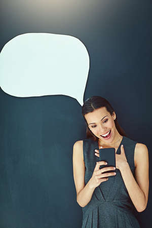 That was unexpected. Shot of a young woman sending a text message against a gray background.