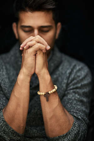 His faith is strong. Closeup shot of a young man praying with his eyes closed.の写真素材