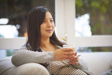 Enjoying a quiet and cozy moment at home. Shot of a pregnant woman looking thoughtful while drinking...
