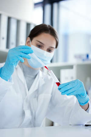 The clinical trial has gone well. Closeup shot of a young woman using a dropper and test tube while...