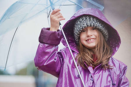 The cold never bothered me anyway. Portrait of a little girl standing under an umbrella outside.の写真素材