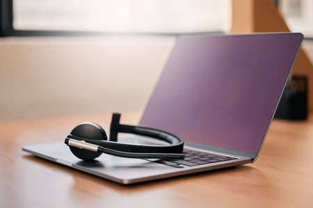 Helping remotely, remotely. Still life shot of a wireless headset and a laptop on a desk in a call center.の写真素材