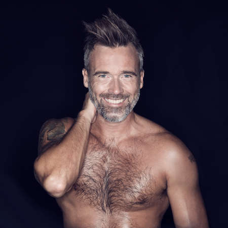 Macho and rugged. Portrait of mature man posing against a dark background.