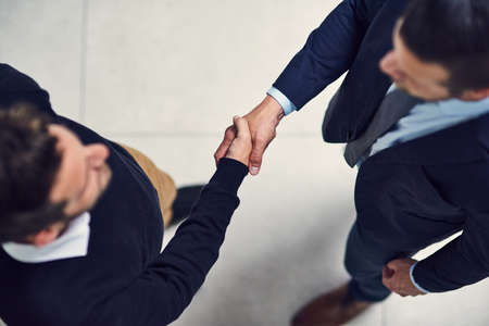 Its been a pleasure doing business with you. High angle shot of two businessmen shaking hands in an office.の写真素材