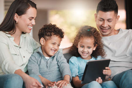 We love this show. Shot of a young family using a digital tablet together at home.