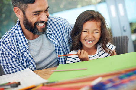Fun-filled creative times. Cropped shot of a father and daughter colouring in together at home.の写真素材