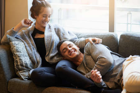 The lap of love. Portrait of a handsome young man lying on his girlfriends lap on the sofa.の写真素材