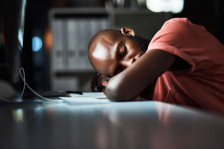 It can be tiring being the hardest worker. Cropped shot of a man falling asleep while working late at the office.の写真素材