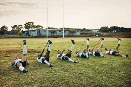 Resistance training pushes you out of your comfort zone. Full length shot of a group of young rugby players training with bands on the field during the day.の写真素材