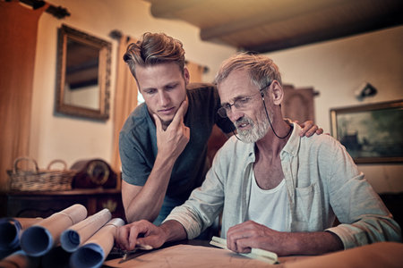 Putting their thinking caps on. Shot of a father and his son working on a design for their family business at home.の写真素材