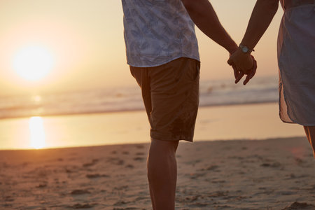 You hand belongs with mine. Rearview shot of a mature couple spending quality time on the beach.の写真素材