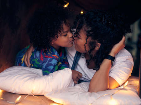 I love you more. Shot of a little boy kissing his mother goodnight.の写真素材