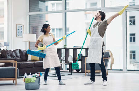 Chores can be fun done with the right one. Shot of a happy young couple having fun while mopping the floor at home.の写真素材