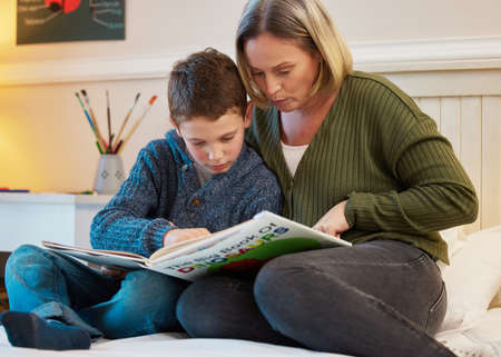 He wants to know all the facts about dinosaurs. Shot of a mother and son reading a book about...