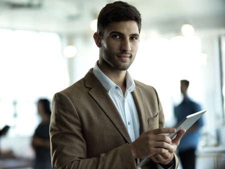 Im a man about my business. Cropped portrait of a handsome young businessman working on a tablet in his office.の写真素材