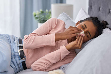 Flu season has arrived. Cropped shot of an attractive young woman lying on her bed at home while...