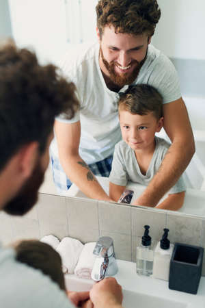 Before you do anything, make sure your hands are clean. Cropped shot of a young handsome father helping his adorable little boy wash his hands in the bathroom at home.の写真素材